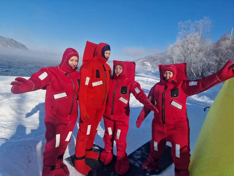 Группа людей в зимних костюмах на льду озера, наслаждающиеся зимним отдыхом.